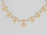 un collier en or orné de feuilles en filigrane sur une chaîne