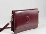 Ce sac à main en cuir marron est muni d'une longue bandoulière et d'une fermeture à fermoir.