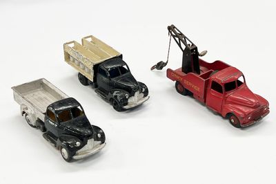 trois camions miniatures placés les uns à côté des autres sur une surface blanche