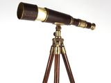 un télescope ancien posé sur un trépied, devant un fond blanc