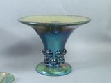 a blue and green vase sitting on a table next to a rock