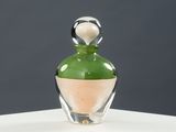 une bouteille en verre avec un bouchon vert posée sur un socle blanc