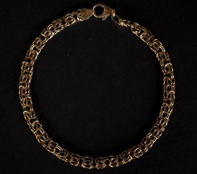 gros plan d'un bracelet en chaîne en or sur fond noir