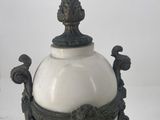 a white vase with a metal handle on a white table