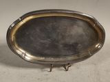 un plat en argent bordé d’or, posé sur un socle, sur un fond blanc