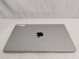 an apple laptop sitting on a bed with a white sheet
