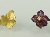 trois boucles d'oreilles clous ornées de fleurs dorées et violettes sur un fond blanc