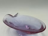 a purple glass bowl sitting on top of a white table