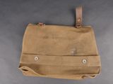 an old brown canvas bag with a leather handle on a gray surface