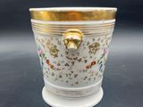 a close up of a gold and white vase on a table