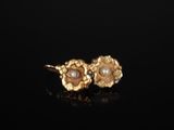 une paire de boucles d'oreilles en or ornées de perles sur un fond noir