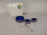 a silver and blue bowl, spoon, and spoon rest on a table