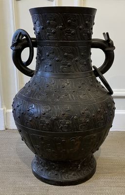 un grand vase noir posé par terre dans une pièce
