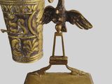 a gold vase with a bird on it and a bird on a stand