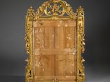 an ornately carved mirror with a wooden frame on a grey background