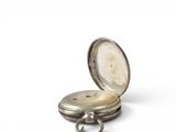a silver pocket watch sitting on a white surface