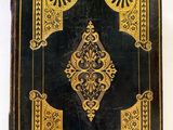 un livre noir et or posé sur une table blanche