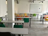 tables and chairs in a room with a white board and a whiteboard