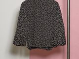 une chemise noire et blanche suspendue à un portant devant un mur rose et blanc