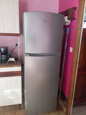 a refrigerator in the corner of a kitchen with a pink wall