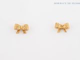 two small gold bow stud earrings on a white surface