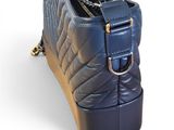 navy blue quilted purse with gold chain strap on white background