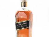 the bottle of black label is sitting on a reflective surface
