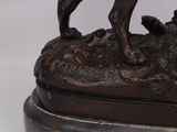 bronze statue of a dog on a rock with a bird on it ' s back