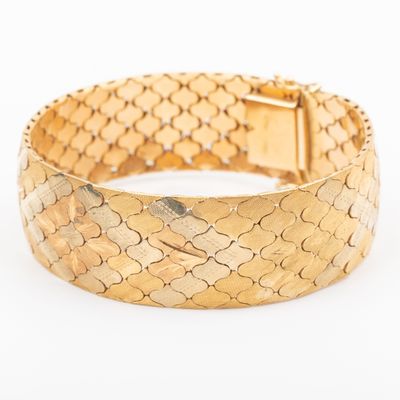 a close up of a gold bracelet on a white background