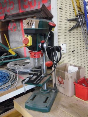 une perceuse posée sur un établi sur lequel sont disposés des outils
