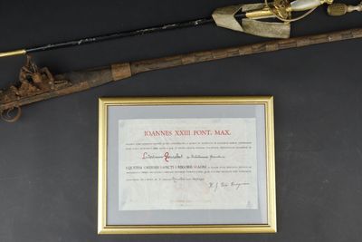 an old gun and a framed certificate are on a table