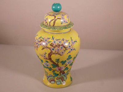 un vase jaune avec un couvercle vert sur lequel est représenté un arbre