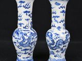 two blue and white vases with dragon designs on them on a black background