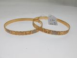 pair of gold tone bracelets with engraved design on each side