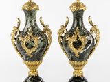 pair of black and gold vases sitting on top of a white surface