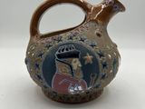 a small ceramic jug with a picture of a man on it