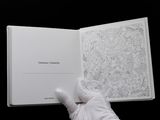 someone in white gloves holding a book with a drawing on it