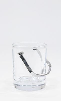 un verre contenant une cuillère, posé sur une surface blanche