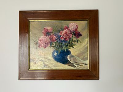un tableau représentant des fleurs dans un vase bleu accroché au mur