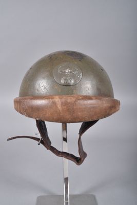un casque métallique posé sur un support muni d'une base en bois