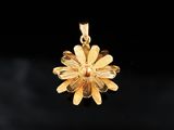 a close up of a gold flower pendant on a black background