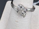 a silver ring with a diamond on it sitting on a ring stand