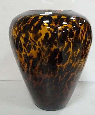 un vase brun et noir posé sur une surface blanche