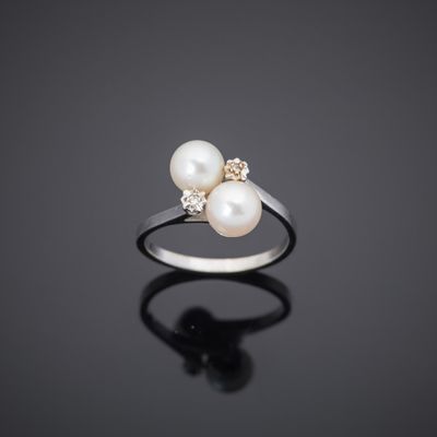 une bague en perles blanches et diamants sur une surface noire