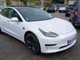 a white tesla model 3 parked in a parking lot
