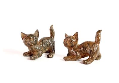 two figurines of cats sitting on a white surface