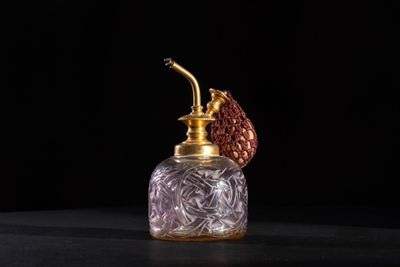 an old fashioned perfume bottle with a red flower on top of it