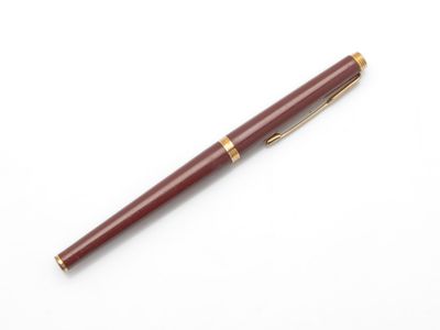 un stylo au corps en bois et aux finitions dorées, posé sur une surface blanche