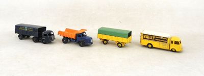 quatre camions miniatures posés les uns à côté des autres sur une surface blanche