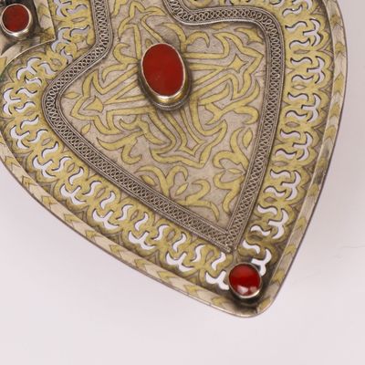 silver and gold heart shaped box with red stones on it